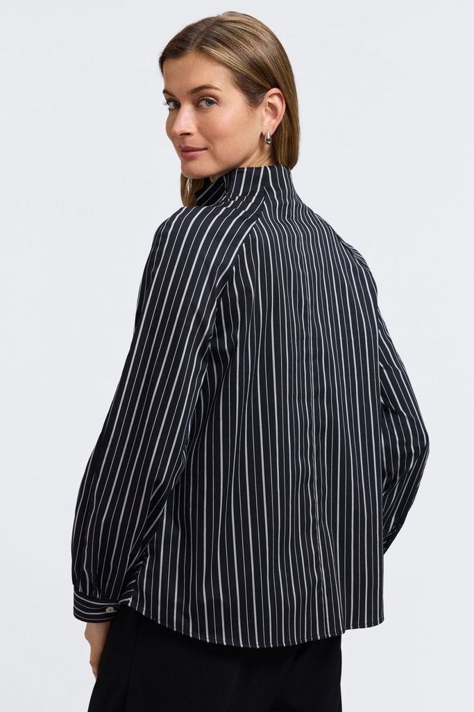 Angled back view of model looking over her shoulder wearing the Daphne Classic Wide Stripe Long Sleeve Popover Shirt #color_black & white wide stripe