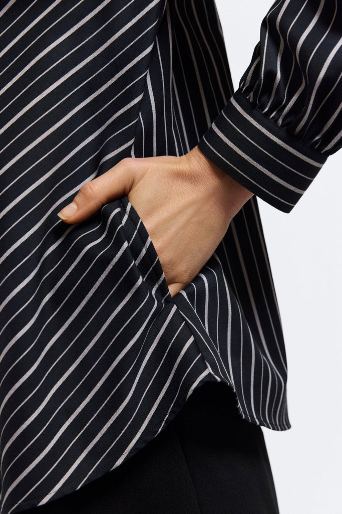 Close up view of models hand in the functioning side pocket of the Daphne Classic Wide Stripe Long Sleeve Popover Shirt #color_black & white wide stripe