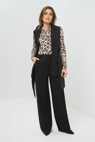 Woman wearing a black suit with a leopard print blouse on a white background