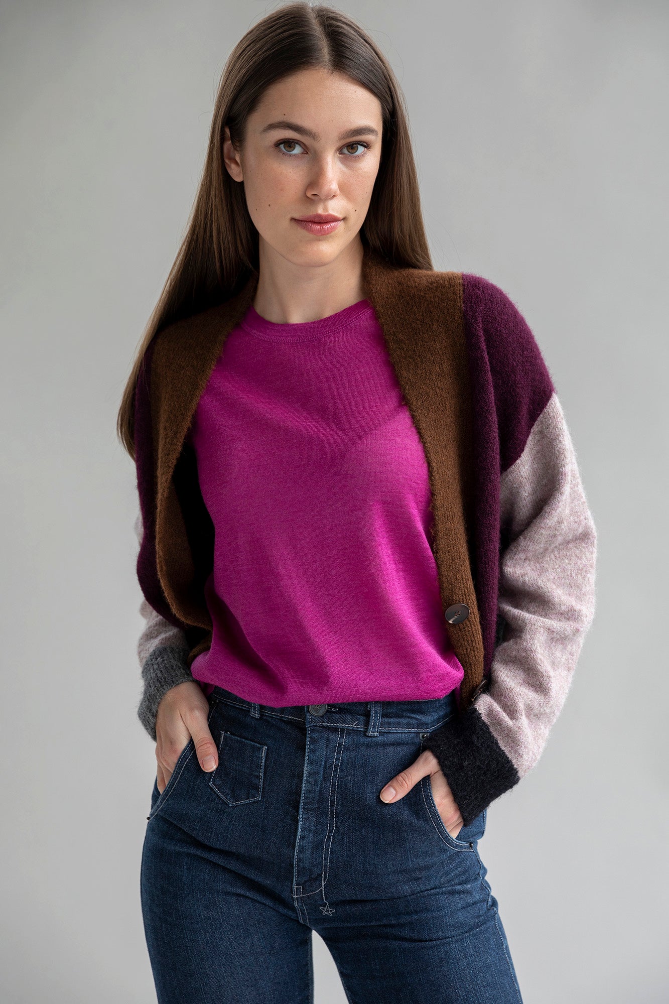 A woman wearing a fuschia colored short sleeve sweater tee made from baby alpaca silk paired with a color block cardigan in aubergine multi color.