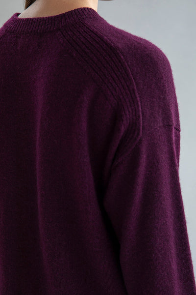 Close-up ribbed details at trims and slits on right side seam of the crew neck boxy pullover in aubergine.