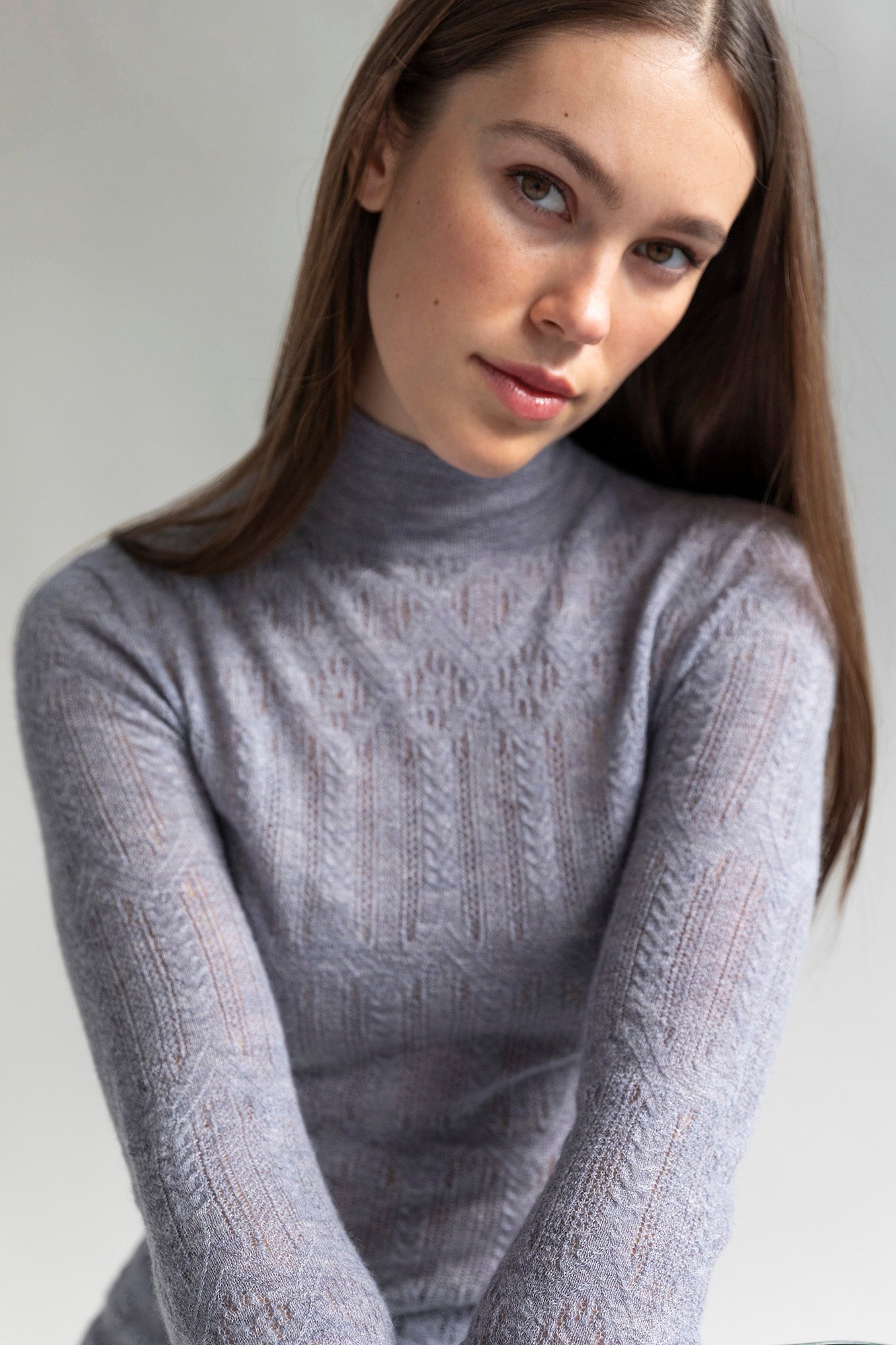Model wearing the Elise Cashmere Pointelle Sweater in glint grey. The sweater features a fitted silhouette, turtleneck, and long sleeves.