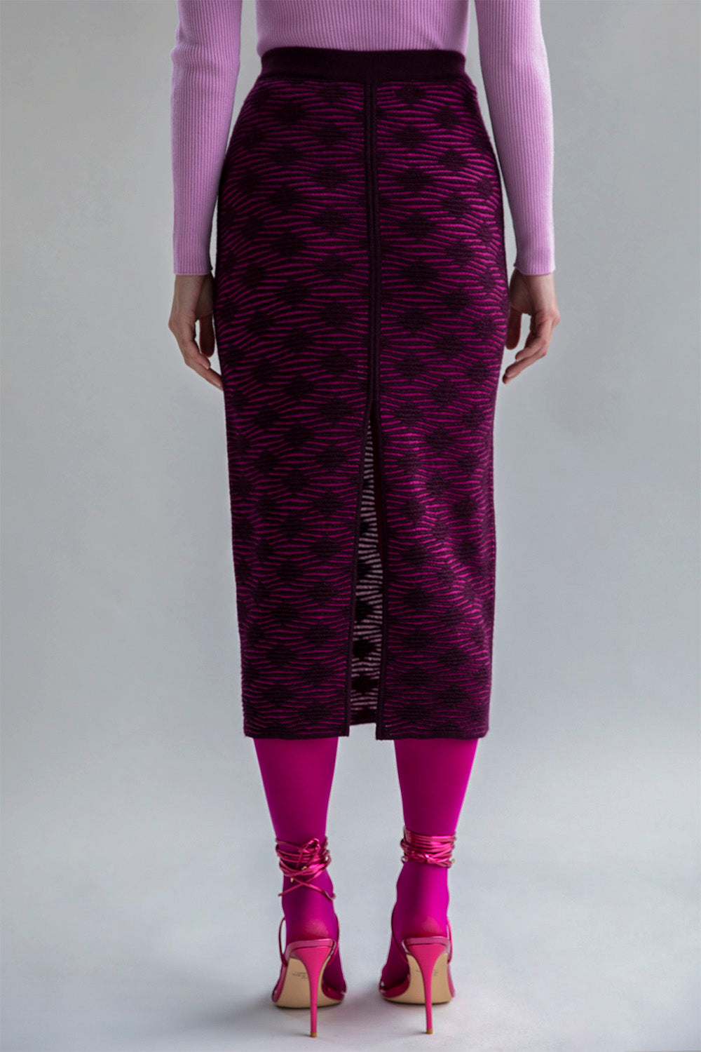 Slim-fitting fuchsia aubergine pencil skirt with a subtle pattern and front slit, styled to show a smooth, streamlined look when worn as intended.