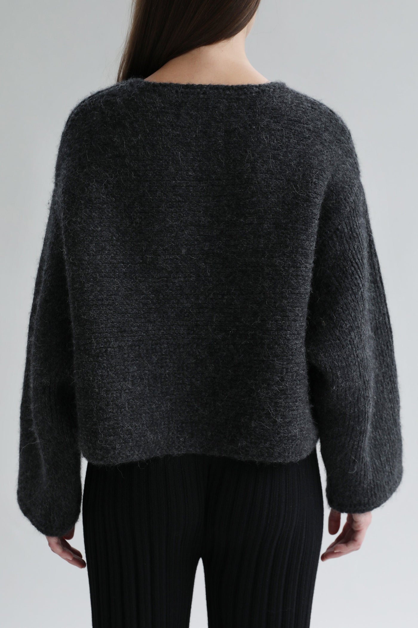 Back view of the Momo Handknit Cardigan in Charcoal, highlighting its relaxed, cropped shape and the artisan-crafted details.