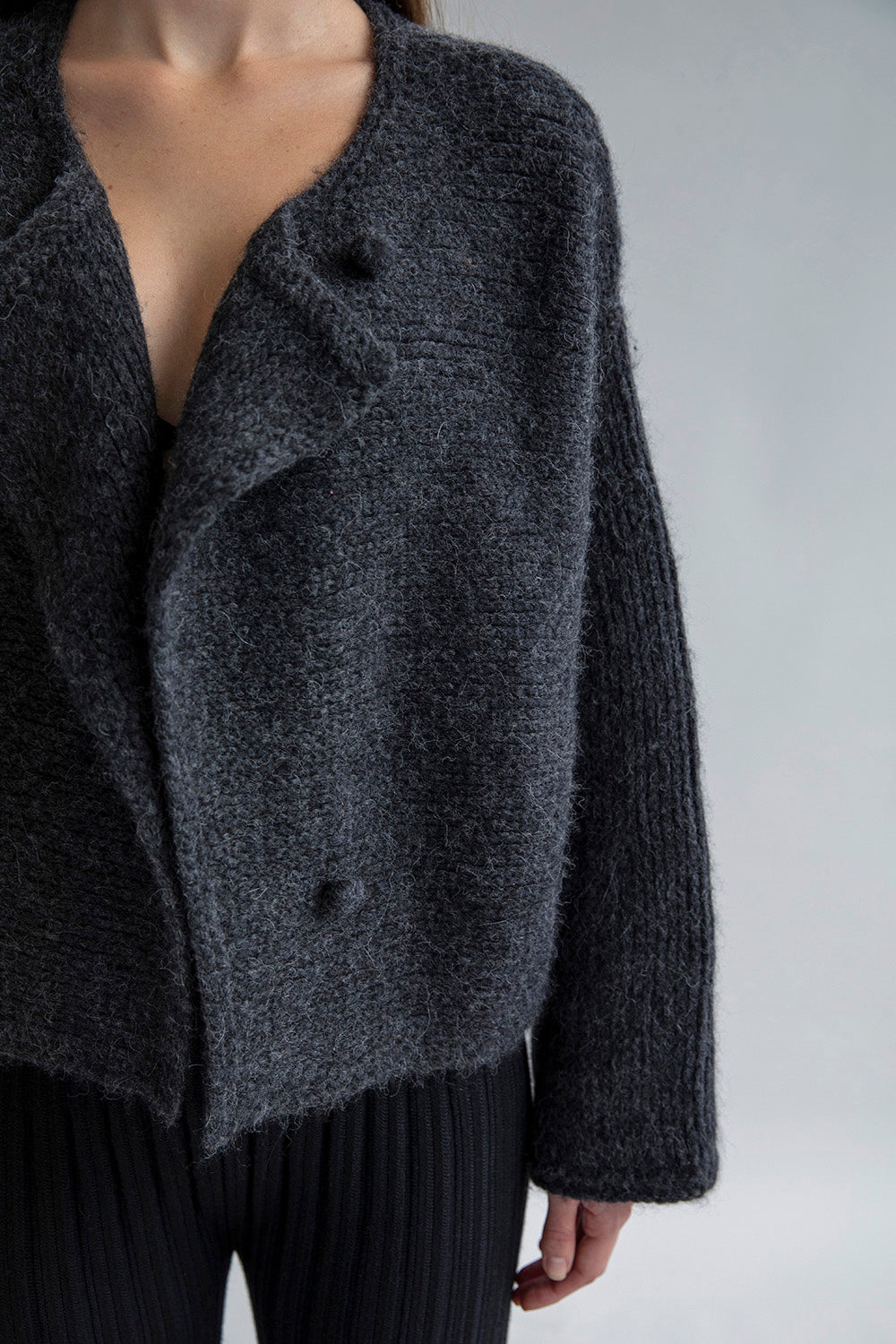 Close-up of the front of the Momo Handknit Cardigan in Charcoal, showing the hand-crocheted buttons made from matching yarn.