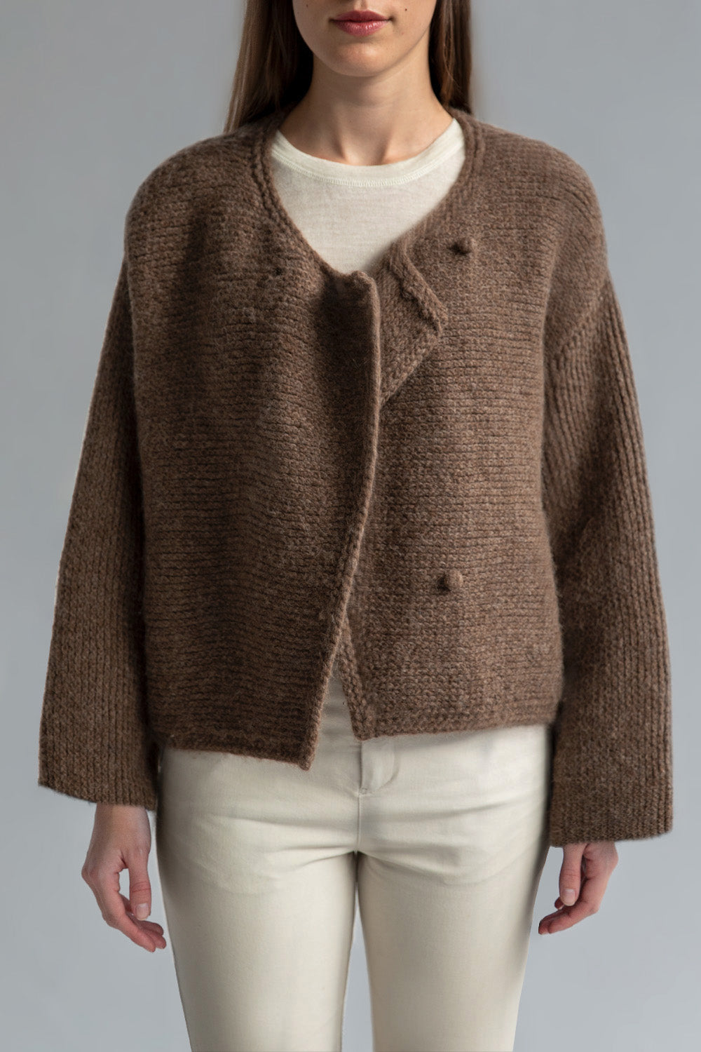 Front view of the Momo Handknit Cardigan in Saddle hand-knitted by Peruvian artisans from soft alpaca blend yarn with a textured stitch. Worn underneath is the Sskein Crew Neck Sweater Tee in Ivory.