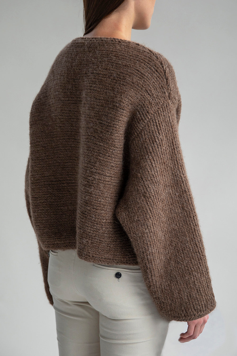 Side view of the Momo Handknit Cardigan in Saddle, showcasing its relaxed, cropped fit and the soft, textured stitch of the alpaca blend yarn.