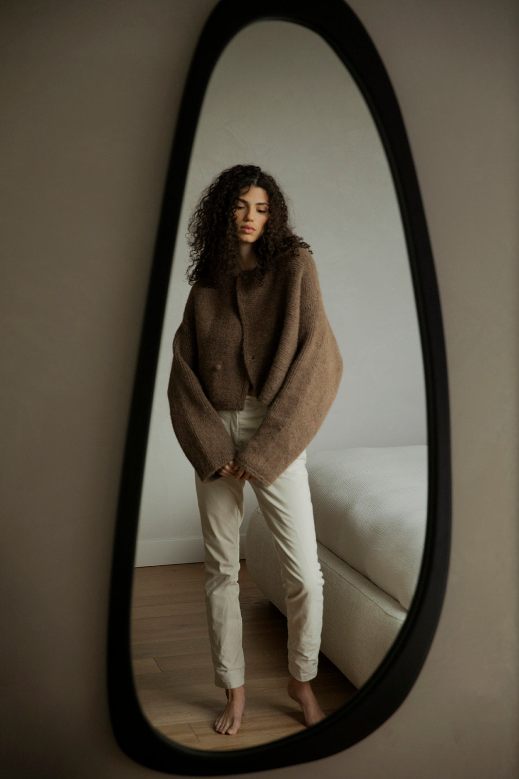 Mirror shot of model in the Momo Handknit Cardigan in Saddle paired with white jeans. A unique cardigan ethically hand-knitted by women artisans in Peru.