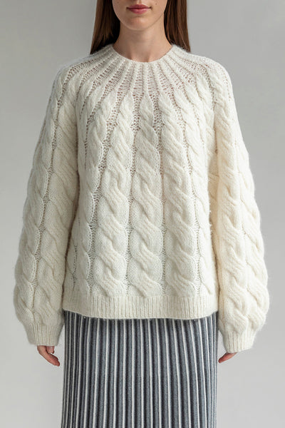 The Tomo Mix Cable Handknit in Ivory. The textured pullover is sustainably made by Peruvian artisans crafted from 70% baby alpaca 23% nylon and 7% merino wool.
