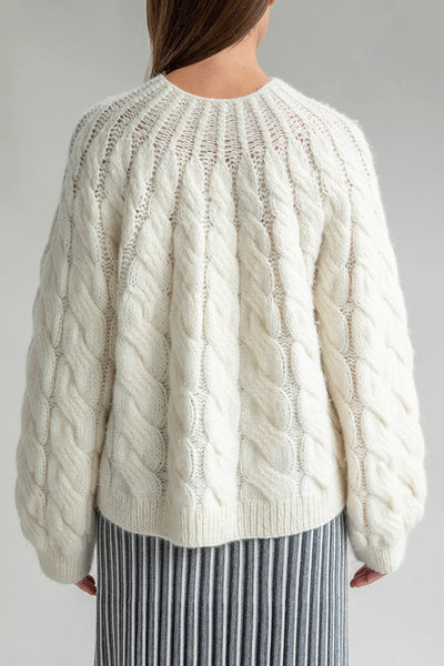 Back view of the Tomo Mix Cable Handknit in Ivory, showcasing its simple design and soft fabric made from an alpaca blend yarn. The pullover has a relaxed fit and ribbed hems.