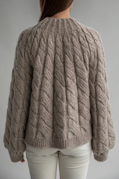 Back view of the Tomo Mix Cable Handknit in Oat Heather showcasing its simple design and soft fabric made from an alpaca blend yarn. The pullover has a relaxed fit and ribbed hems.