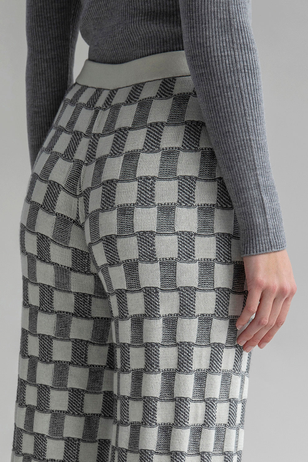 Close-up shot of Zoe Alpaca Trousers in light grey and ivory, highlighting the graphic-checked jacquard pattern and the soft blend of 62% baby alpaca and 38% Pima cotton